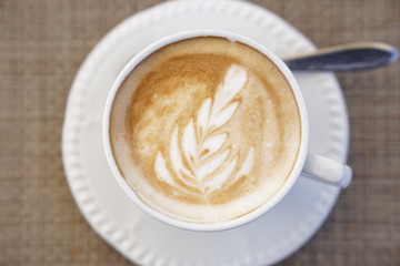 Close up coffee in a white cup from above with a nice art drawing on the surface