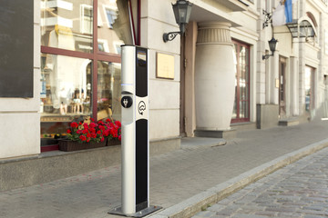 Fototapeta premium Electric vehicle charging (Ev) station with plug of power cable supply for Ev car. Electric Eco car charger in the city