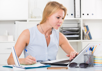 portrait of girl business manager writing and working with laptop in office workplace