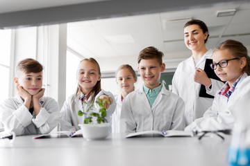 education, science and school concept - kids or students and teacher with plant at biology class