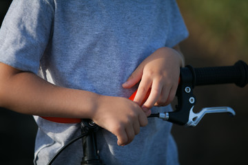  The boy stopped on a bicycle and held onto the steering wheel. Close-up.