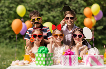 holidays, childhood and celebration concept - happy kids with party props at summer birthday