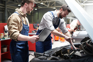 Portrait handsome of two workers fixing car in service workshop and smiling happily, copy space