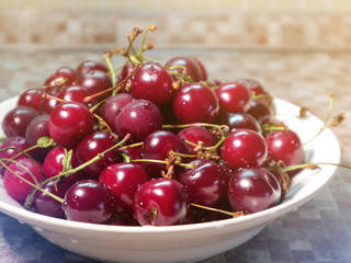 Ripe red fresh cherry in sunlight in a dish