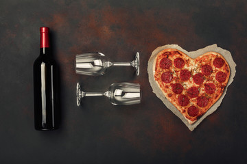 Heart shaped pizza with mozzarella, sausagered , wine bottle and two wineglass. Valentines day greeting card on rusty background