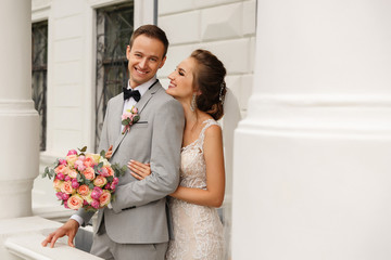 Happy wedding couple embracing and smiling after wedding ceremony near castle. Elegant bride and...