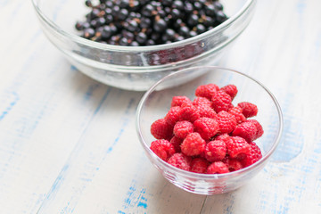 Berries of raspberries and black currants. Fresh summer berries in plates.