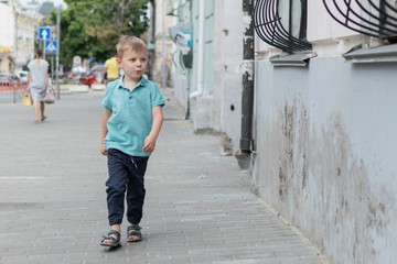 A little boy is walking along the city street.