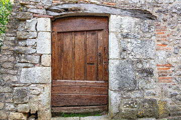 Fototapeta na wymiar Vieille porte médiévale en bois dans un mur de pierre
