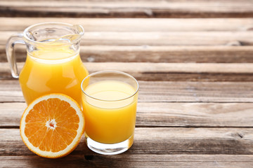 Orange fruit with jug and glass of juice on brown wooden table