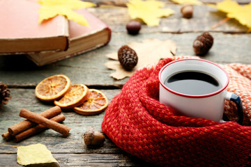 Cup of coffee with red scarf, cinnamon and dried oranges on wooden table