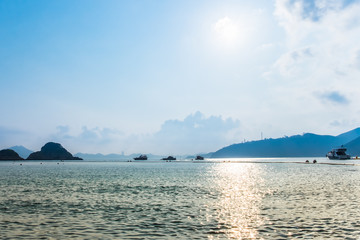 Beautiful sunset over the sea with pleasure boats silhouettes and islands on horizon line. Golden sun road glittering on water surface. Peaceful, tranquil landscape.