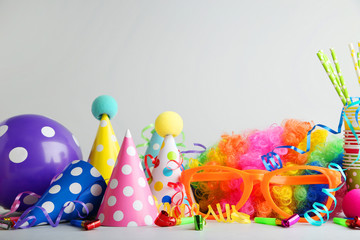 Birthday party caps, blowers and balloons on grey background