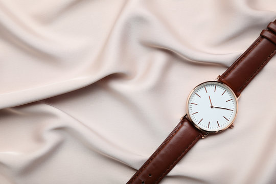 Wrist watch on beige satin background