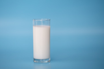 A bottle of milk and glass of milk on  blue background.