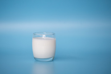 A bottle of milk and glass of milk on  blue background.