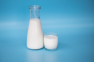 A bottle of milk and glass of milk on  blue background.