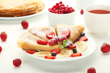 Pancakes with berries on white wooden table