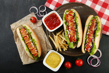 Hot dogs with vegetables and french fries on wooden table