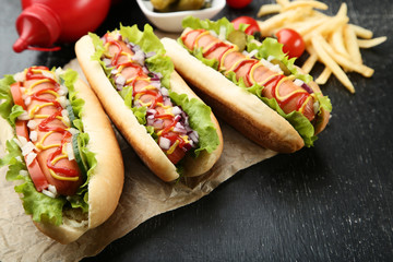 Hot dogs with ketchup, mustard and vegetables on wooden table