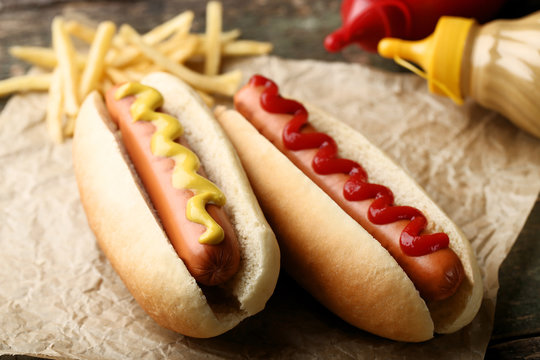 Hot dogs with mustard and ketchup on wooden table