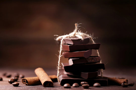 Chocolate pieces with coffee beans and cinnamon on wooden table