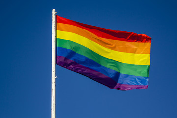 LGBT rainbow pride flag against blue sky