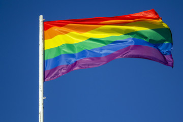 LGBT rainbow pride flag against blue sky