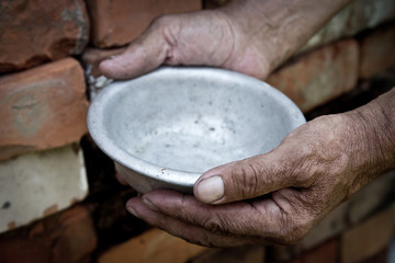 The poor old man's hands hold an empty bowl. The concept of hunger or poverty. Selective focus....