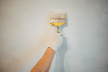 A man's hand with a brush with white door paint. Selected focus