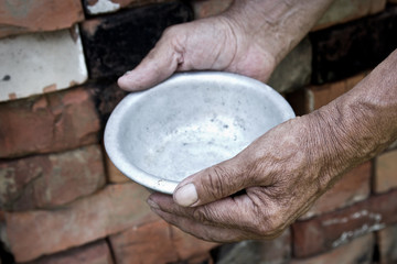 The poor old man's hands hold an empty bowl. The concept of hunger or poverty. Selective focus. Poverty in retirement.Homeless. Alms