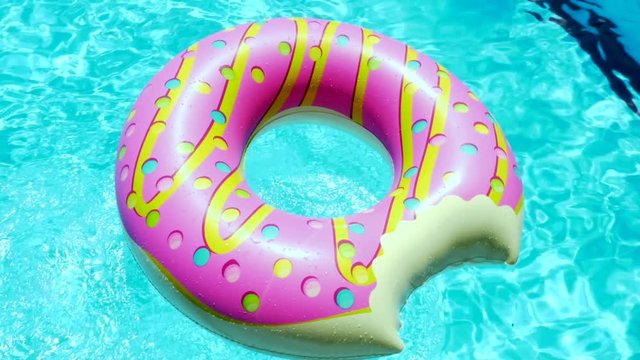 Inflatable Donut pool toy in a blue swimming pool on sunny day