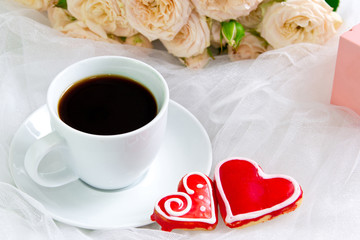 Valentine's day. Wedding . A Cup of coffee and two gingerbread heart on a background of roses.