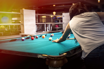 Brunette woman playing billiard, making a hit