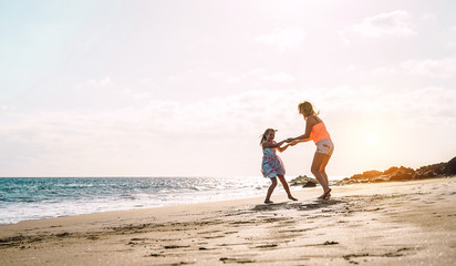 Happy loving family mother and daughter having fun on the beach at sunset - Mum playing with her...