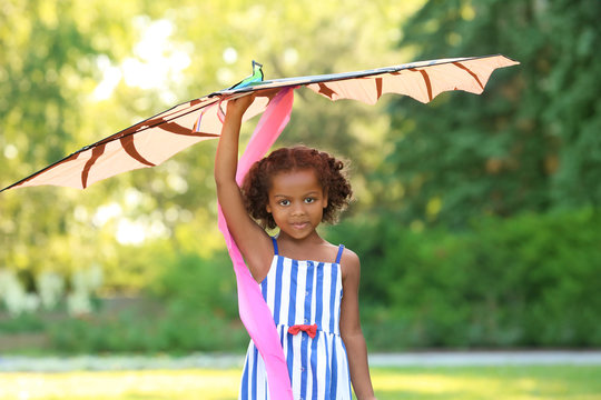 Cute African American girl playing with kite outdoors