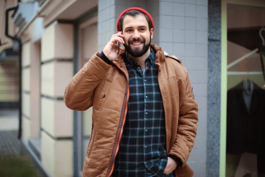 Handsome trendy hipster talking on mobile phone outdoors