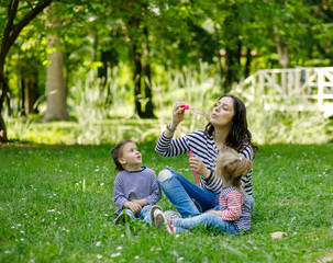 Naklejka na ściany i meble Happy mother and daughters in the park. Beauty nature scene with family outdoor lifestyle.