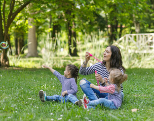 Fototapeta na wymiar Happy mother and daughters in the park. Beauty nature scene with family outdoor lifestyle.