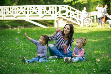 Happy mother and daughters in the park. Beauty nature scene with family outdoor lifestyle.