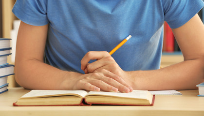 Teenager boy doing homework in library, closeup
