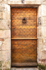 Naklejka premium Vieille porte médiévale en bois dans un mur de pierre