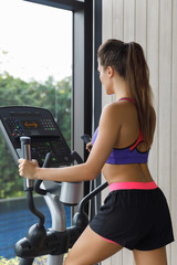 Sporty is woman using elliptical trainer