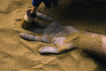 Forensic expert discovering dead body buried in desert sand