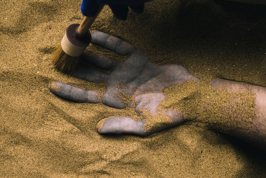 Forensic Expert Discovering Dead Body Buried In Desert Sand