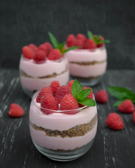 Sweet raspberry mousse in glass bowl on dark background