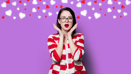 portrait of the beautiful young surprised woman with hearts on the violet background