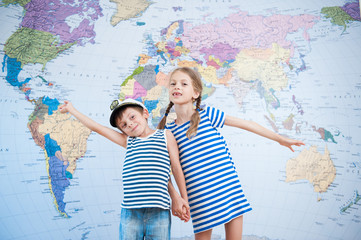 two happy cute kids in striped sailor shirts on world map background