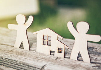 little wooden men and house on natural background. Symbol of construction, family, sweet home concept
