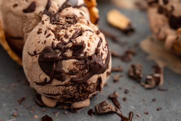 Homemade chocolate ice cream in waffle cones, with a spoon for ice cream, cocoa and pieces of dark chocolate. On a dark gray table. Copy space close view